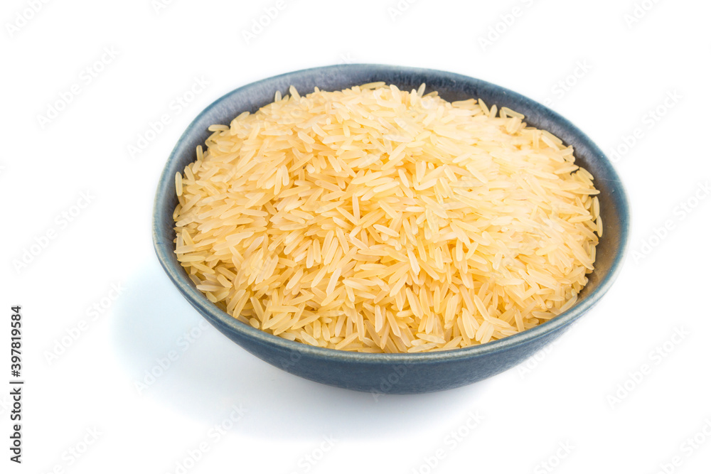Blue ceramic bowl with raw golden rice isolated on white background. Side view. Blue ceramic bowl with raw golden rice isolated on white background. Side view.
