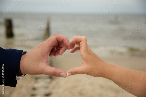 Paar formt Herz mit Fingern an der Ostsee photo