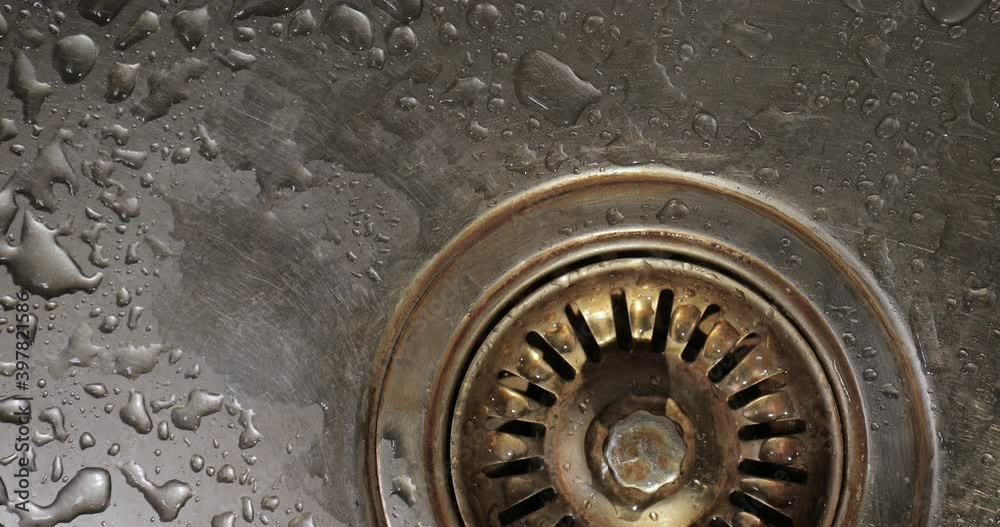 Dripping kitchen faucet over sink, water drops hiting the basin Dripping kitchen faucet over sink, water drops hiting the basin