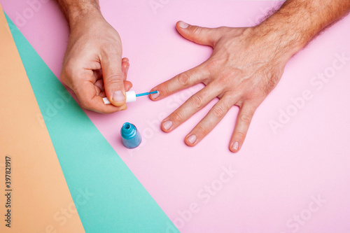 Male hands are doing a manicure on a pink background. Lgbt concept. Personal care. View from above