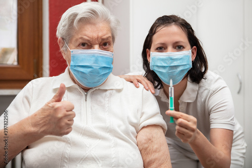 elderly senior woman and a female nurse show that they are in favor of a vaccination
