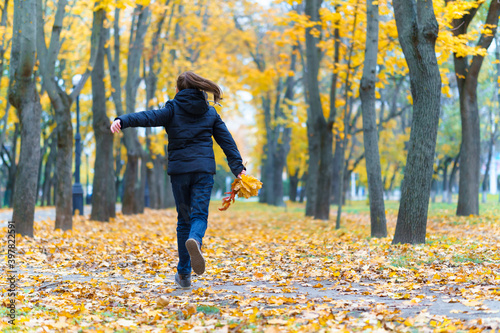 a girl running through the park and enjoys autumn, beautiful nature with yellow leaves © soleg
