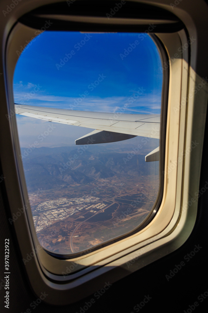 View from the porthole window flying airplane on the airplane wing. Flying and traveling concept