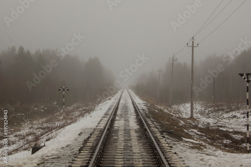 Railway line in the fog. Rails, poles and road signs are lost in the fog. Autumn foggy day over the railroad.