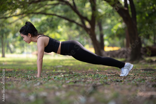 Young Asian woman doing push-ups in park, sport and healthy lifestyle concept