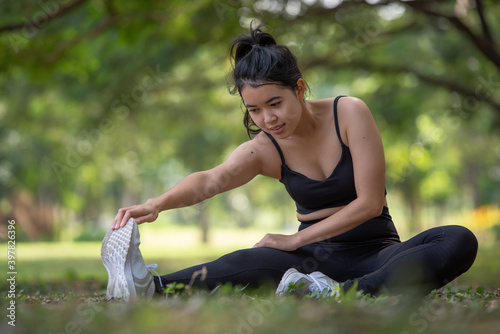 Young Asian woman doing stretching warm up before exercise outdoors in park, sport and healthy lifestyle concept