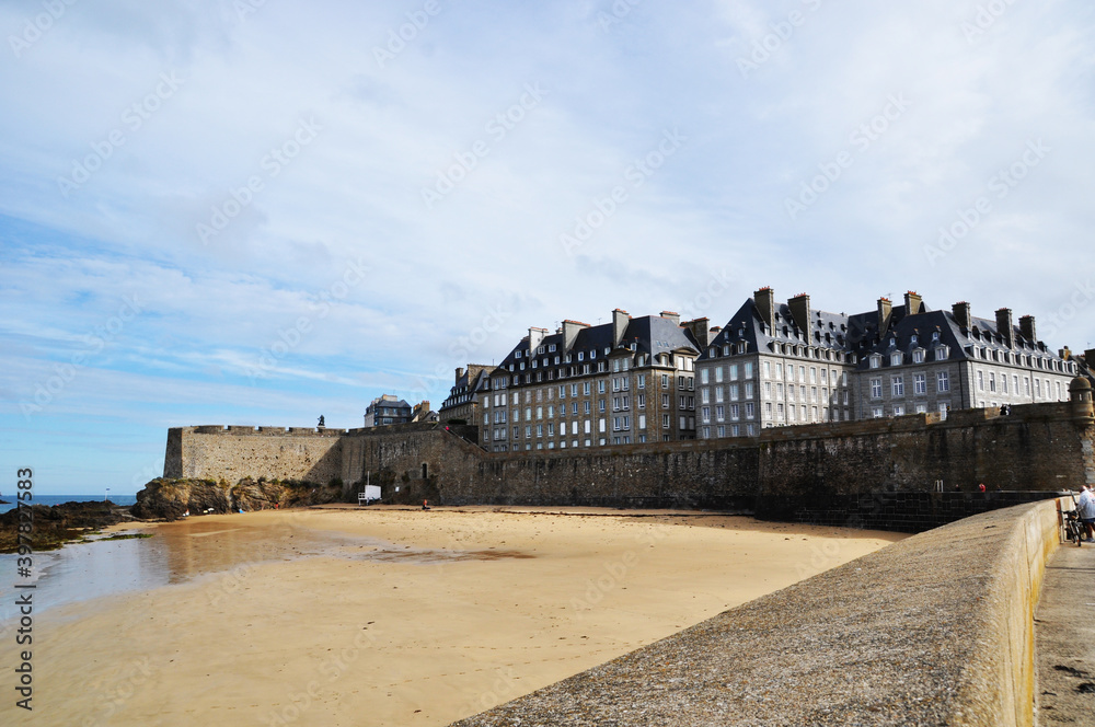 View of the buildings of the fortress Saint-Malo, France. Sandy seashore at low tide.