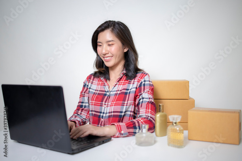 A young Asian businesswoman packing products in a package according to the order the customer has ordered.  © Worranan
