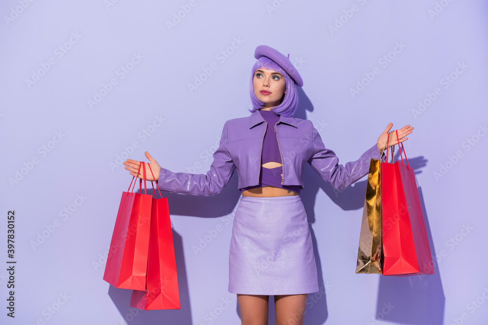young woman dressed in doll style with red shopping bags on violet colorful background