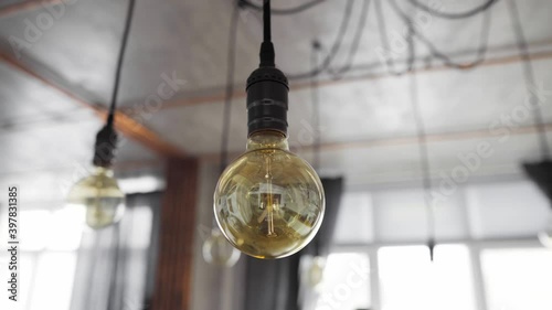 Big vintage incandescent light bulbs hanging in modern kitchen. Decorative antique edison light bulbs with straight wire. Inefficient filament light bulbs waste electricity. Warm white, dimmable, E27 photo