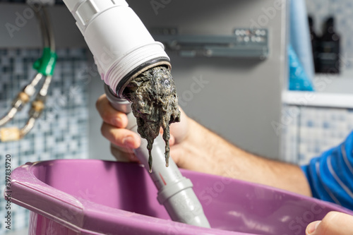 Canvas Print The plumber removes the blockage in the pipes, disassembles the siphon, pulls out the dirt