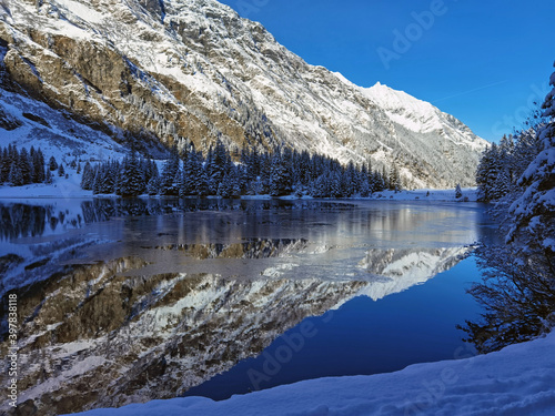 wonderful winter landscape in the snow capped alps with a mountain lake and a beautiful reflection on the water