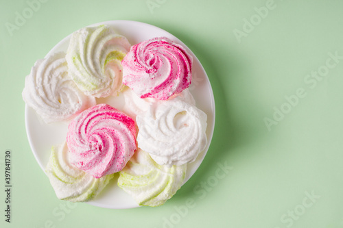 Homemade sweet colored meringue on green background. .Dessert.