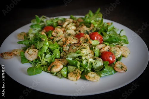 green salad with shrimps and cherry tomatoes on a white plate