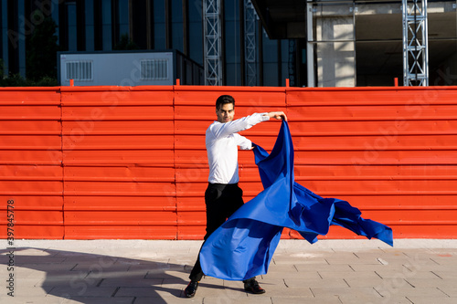 Businessman swinging blue cloth on pavement in the city