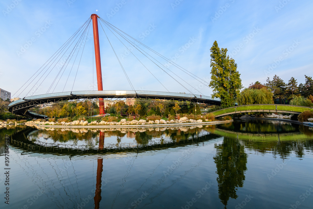 Landscape with the lake and suspended bridge from Drumul Taberei Park, also known as Moghioros Park, in Bucharest, Romania, at sunrise in an autumn morning.