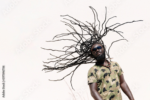 Rastafari man with sunglsasses tossing his dreadlocks photo
