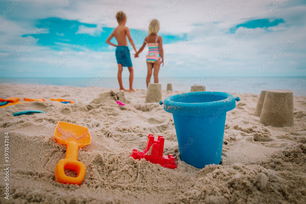 kids toys and castle on beach, boy and girl holding hands kids toys and castle on beach, boy and girl holding hands