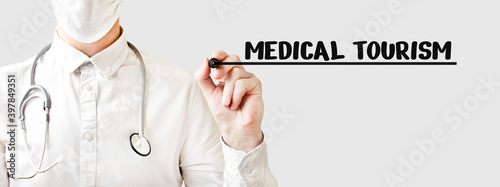Doctor writing word MEDICAL TOURISM with marker, Medical concept