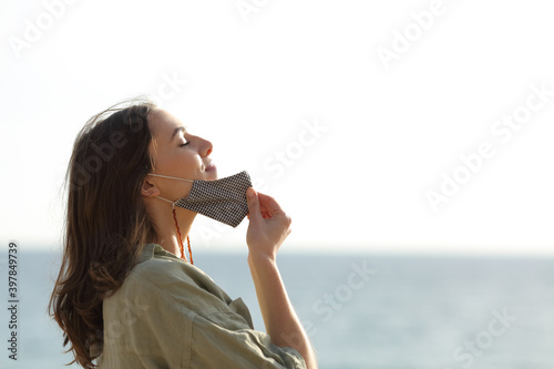 Woman breathing taking off mask due covid on the beach photo