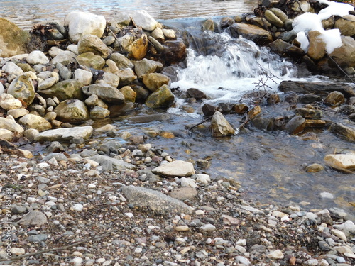 streem and stones in the water in winter on summer dam on river