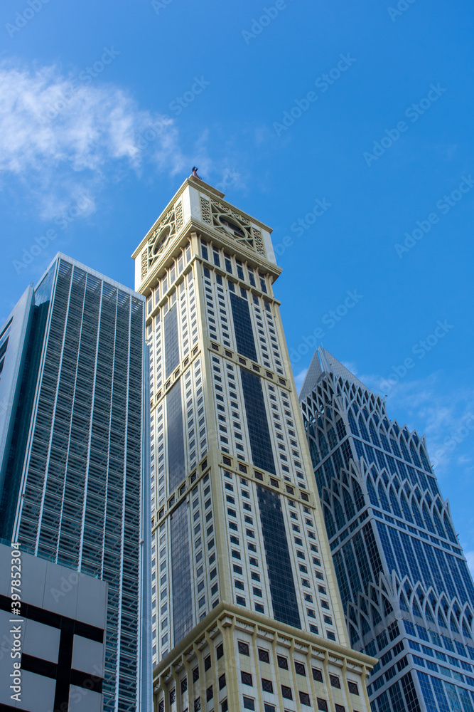 Dubai International Financial Centre (DIFC)  Iconic The Tower (clock) amid modern Dubai skyscrapers on blue sky.