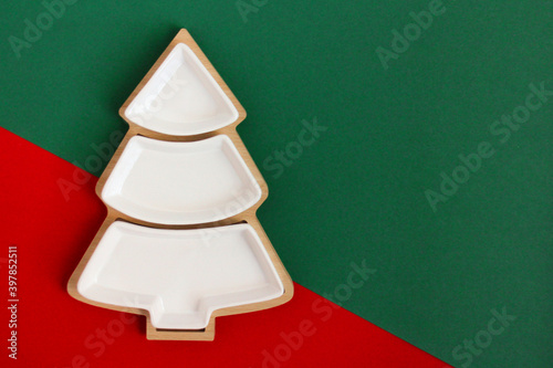 Empty plate in the shape of a Christmas tree on a red and green background.The view from the top.