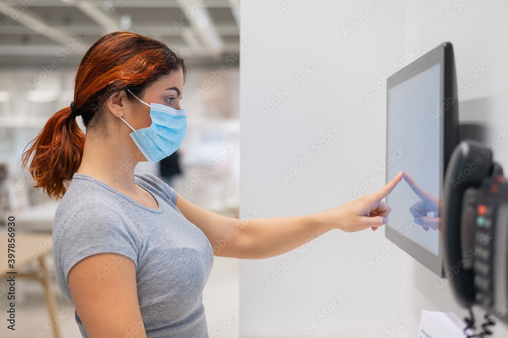 The new norm after the coronavirus epidemic is a woman looking for information with a digital touch screen in a store The new norm after the coronavirus epidemic is a woman looking for information with a digital touch screen in a store