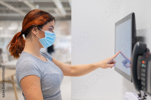 The new norm after the coronavirus epidemic is a woman looking for information with a digital touch screen in a store