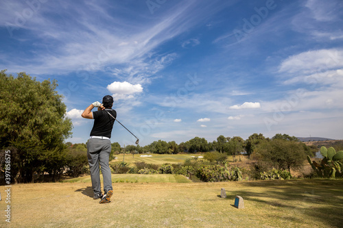 young golf player hitting the ball, blue sky