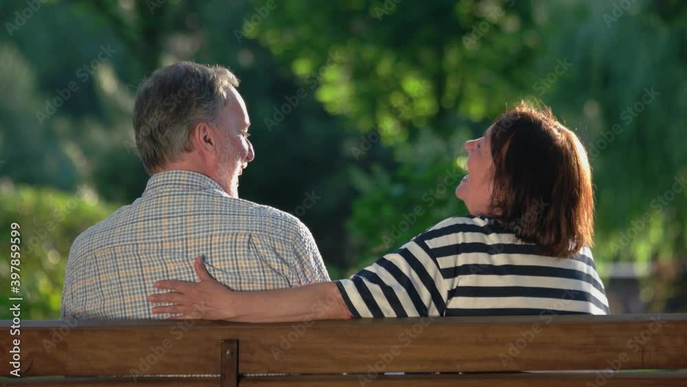 Older man and woman having happy time together. Retired man and woman having fun sitting on bench at park. Beautiful moments with beloved people. Older man and woman having happy time together. Retired man and woman having fun sitting on bench at park. Beautiful moments with beloved people.