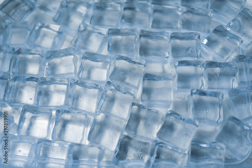 Selective focus, blurred background. Top above overhead close up macro view photo of ice cubes and water drops on blue background. High quality photo