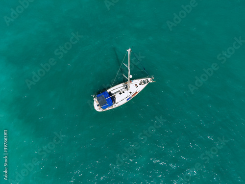Aerial wonderful view of a enormous white and blue yacht sailing across the blue lagoona