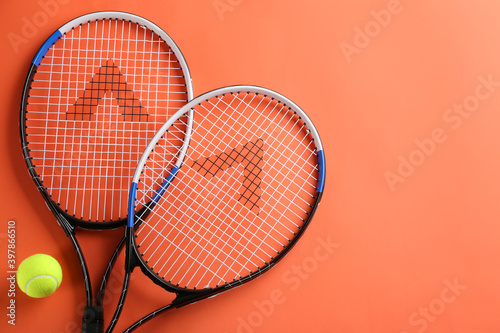 Tennis rackets and ball on orange background, flat lay. Space for text © New Africa