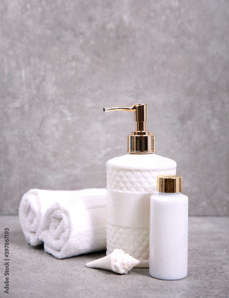 Towels and cosmetic bottles on grey stone background.Shower set,spa products,body care and hygiene. Towels and cosmetic bottles on grey stone background.Shower set,spa products,body care and hygiene.
