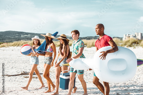 Group of friends spending time on the beach together celebrating. People enjoying the mediterranean sea and the nature. Concept about vacations and lifestyle