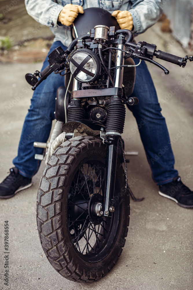 Naklejka premium The front part of the motorcycle wheel with the rider sitting with the lamp with tape cross over optic. Motorcycles to order. Outdoor concept