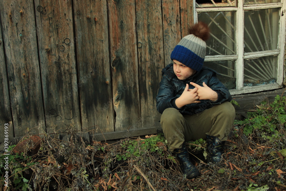 Fototapeta premium Lonely child is sitting next to the broken window