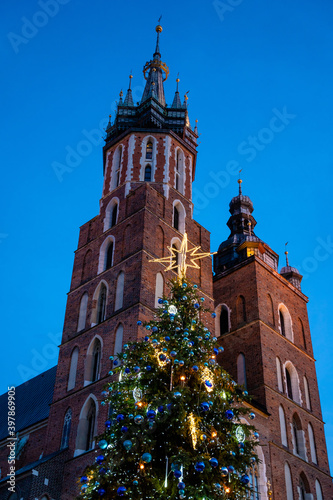 Big glowing decorated christmas tree standing in main market square, winter holidays, peoples enjoy.