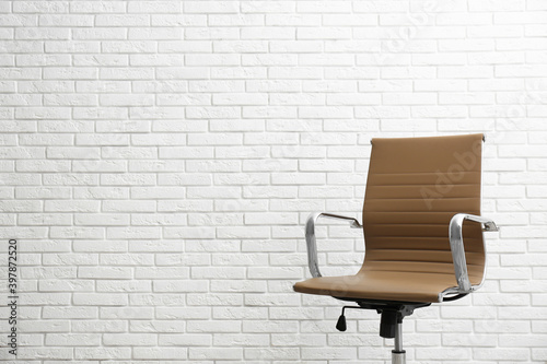 Comfortable office chair near white brick wall. Space for text