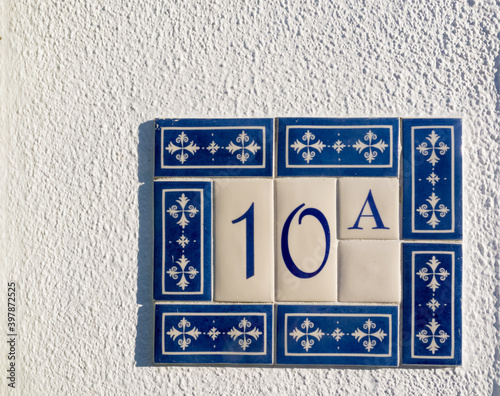 number 10 on a wall surrounded by ceramic decorative tiles as a house number