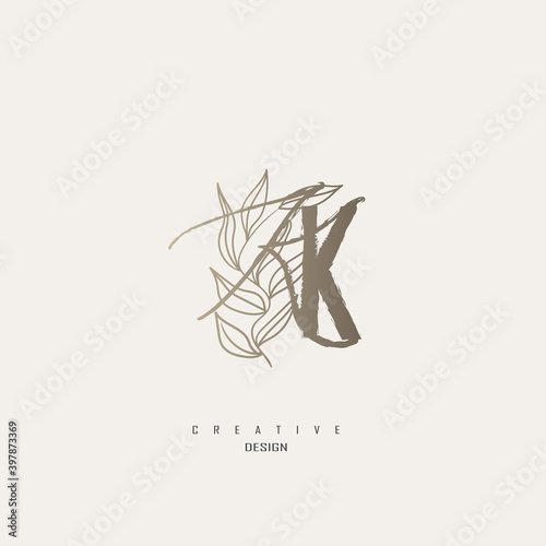 logo kk dengan warna emas, logo terinspirasi dari daun dan kuas.