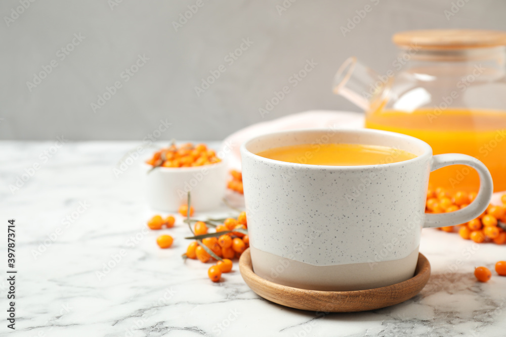 Delicious sea buckthorn tea and fresh berries on white marble table. Space for text Delicious sea buckthorn tea and fresh berries on white marble table. Space for text