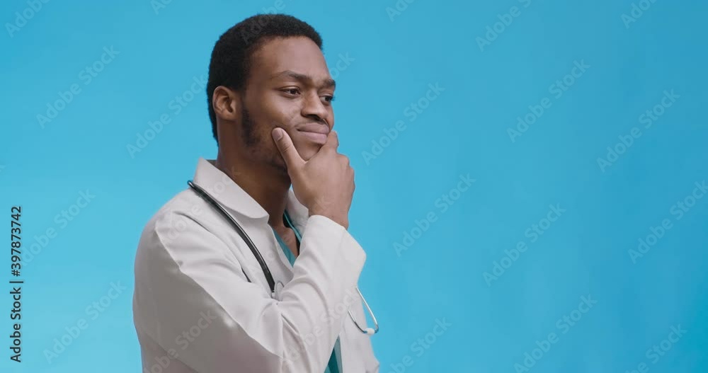 Studio portrait of thoughtful african american doctor thinking over hard medical case, blue background Studio portrait of thoughtful african american doctor thinking over hard medical case, blue background