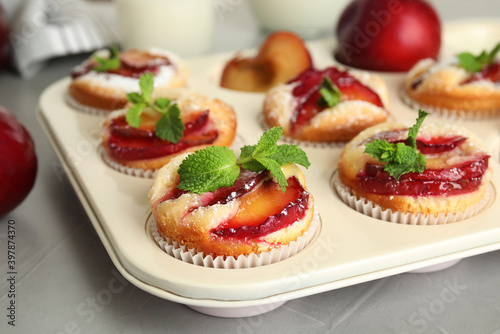 Delicious cupcakes with plums in baking pan, closeup