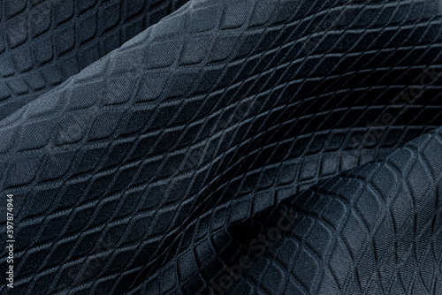 Background made from a macro of real material in dark blue, diamond shapes.