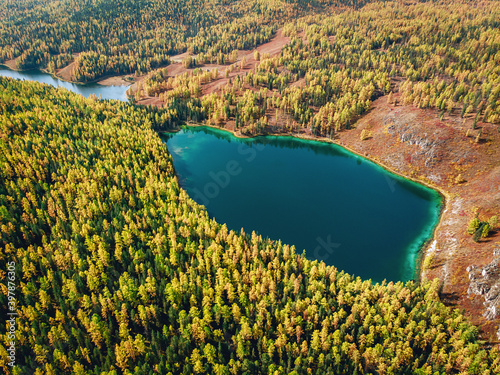 Bird view of a huge lake with brilliant turquoise water which is located right in the middle of a dense saturated forest
