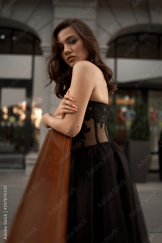 Full-length portrait of an elegant brunette woman with long hair in a black long evening dress. Full-length portrait of an elegant brunette woman with long hair in a black long evening dress.