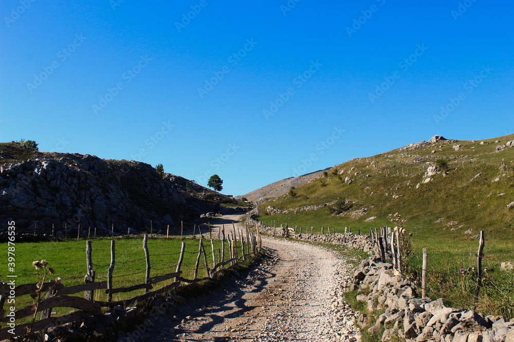 Autumn on the mountain. The road is surrounded by stone with wooden pillars connected by barbed wire. Mountain road that leads to the old Bosnian village of Lukomir.