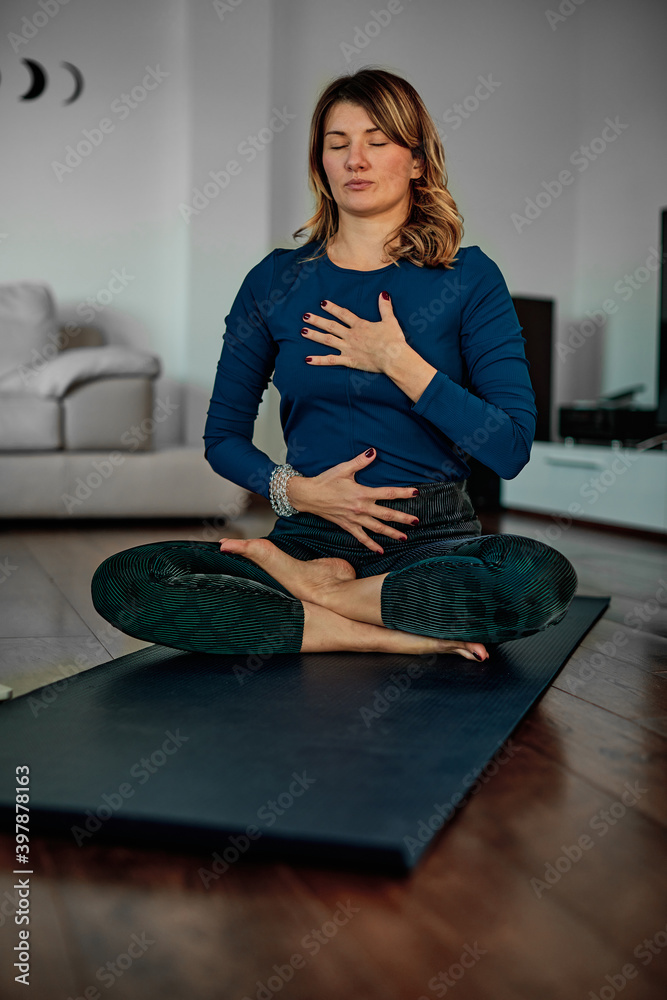 © chika_milan - A middle-aged woman sitting in lotus yoga posture and doing breathing exercises.a © chika_milan - A middle-aged woman sitting in lotus yoga posture and doing breathing exercises.a